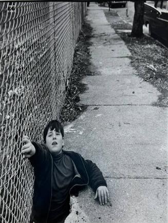 A Boy Climbing Through a Hole in the Sidewalk, NY
