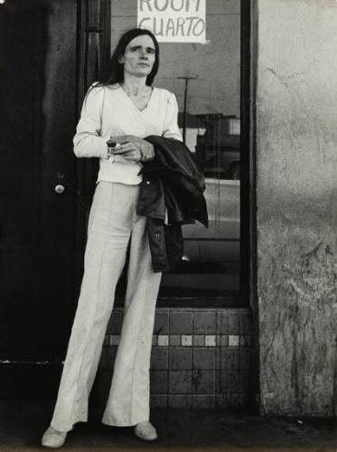 California (tall, thin woman in white in front of "rooms/cuartos" sign)