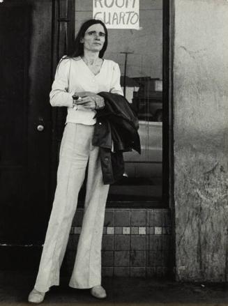 California (tall, thin woman in white in front of "rooms/cuartos" sign)