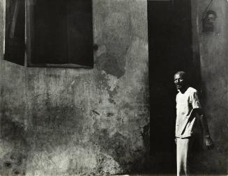 untitled (Haiti, man in white shirt standing against wall)