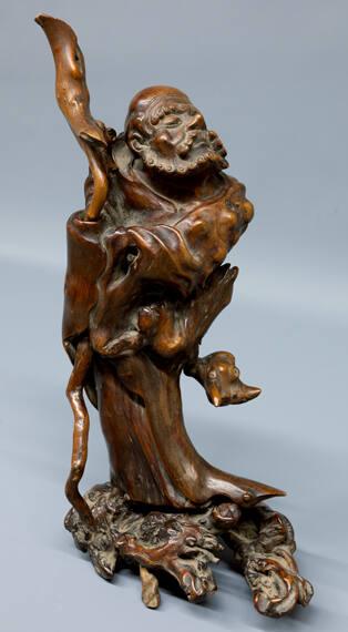 Chinese Okimono of Lacqured Burled Wood, Depicting a Standing Man with Staff, Head Raised